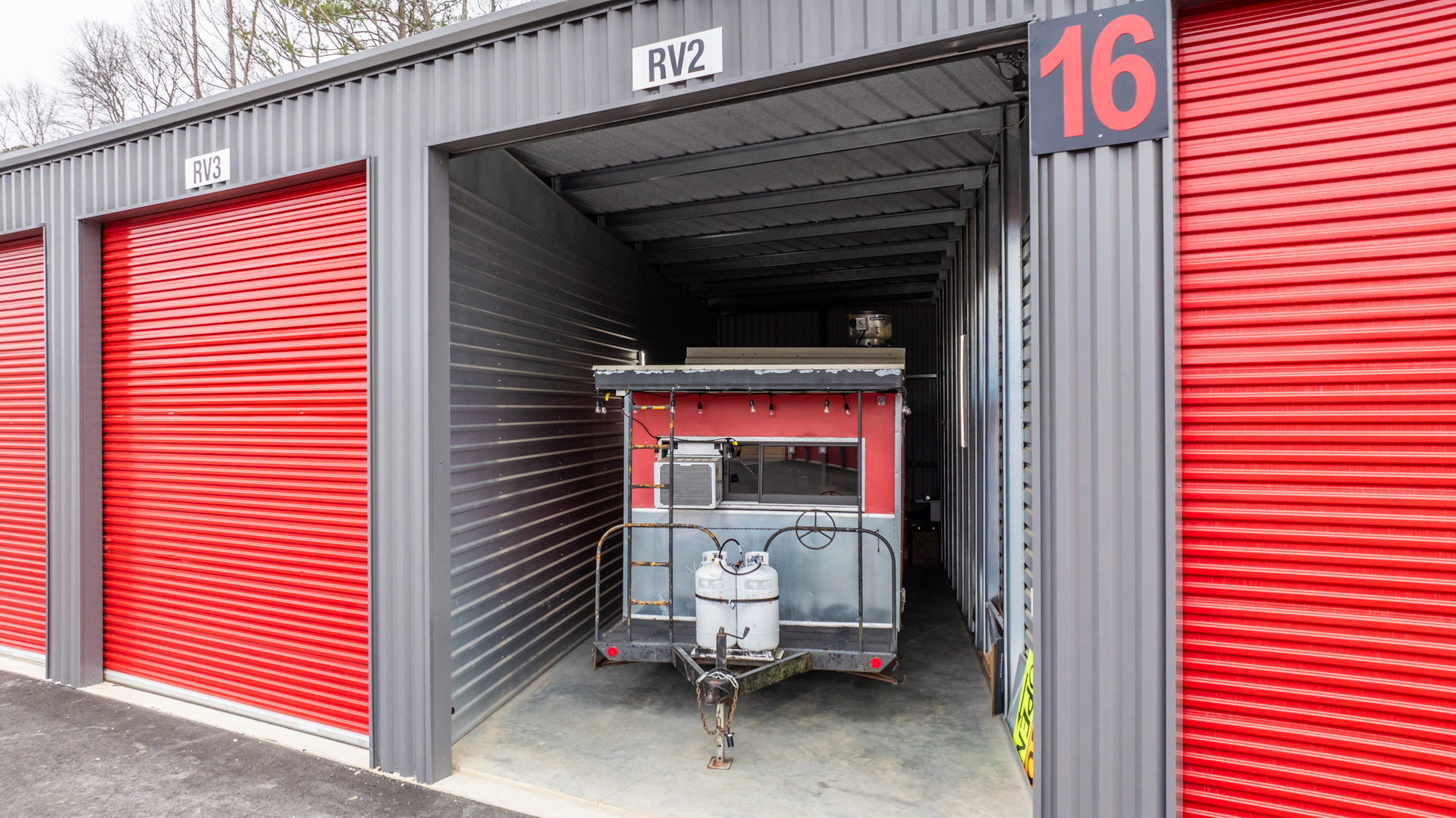 Modern Storage® Shackleford drive-up storage units with wide paved driveways, red roll-up doors, and gated secure access in Little Rock, Arkansas.